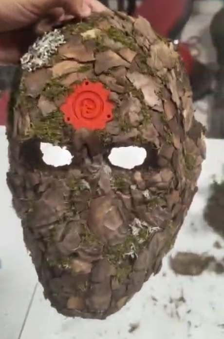 Máscara de corteza y musgo con un Orticoin rojo en la frente